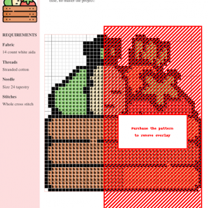 Cross-stitch pattern of a crate overflowing with fresh vegetables. The design uses brown, green, and orange threads on white aida cloth.