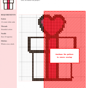 Cross stitch pattern design depicting a gift with a heart on top, predominantly in red and black threads on white aida fabric.