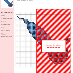 Cross stitch pattern design showcasing a modern abstract shape in shades of blue on a white aida cloth. A red overlay obscures part of the design.